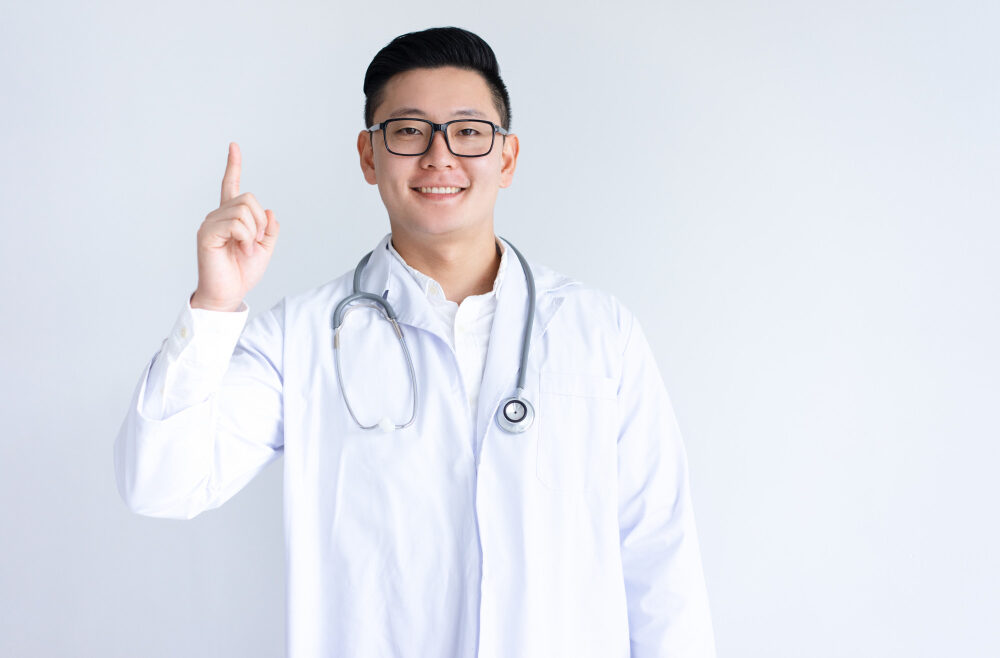 smiling-asian-male-doctor-pointing-upwards